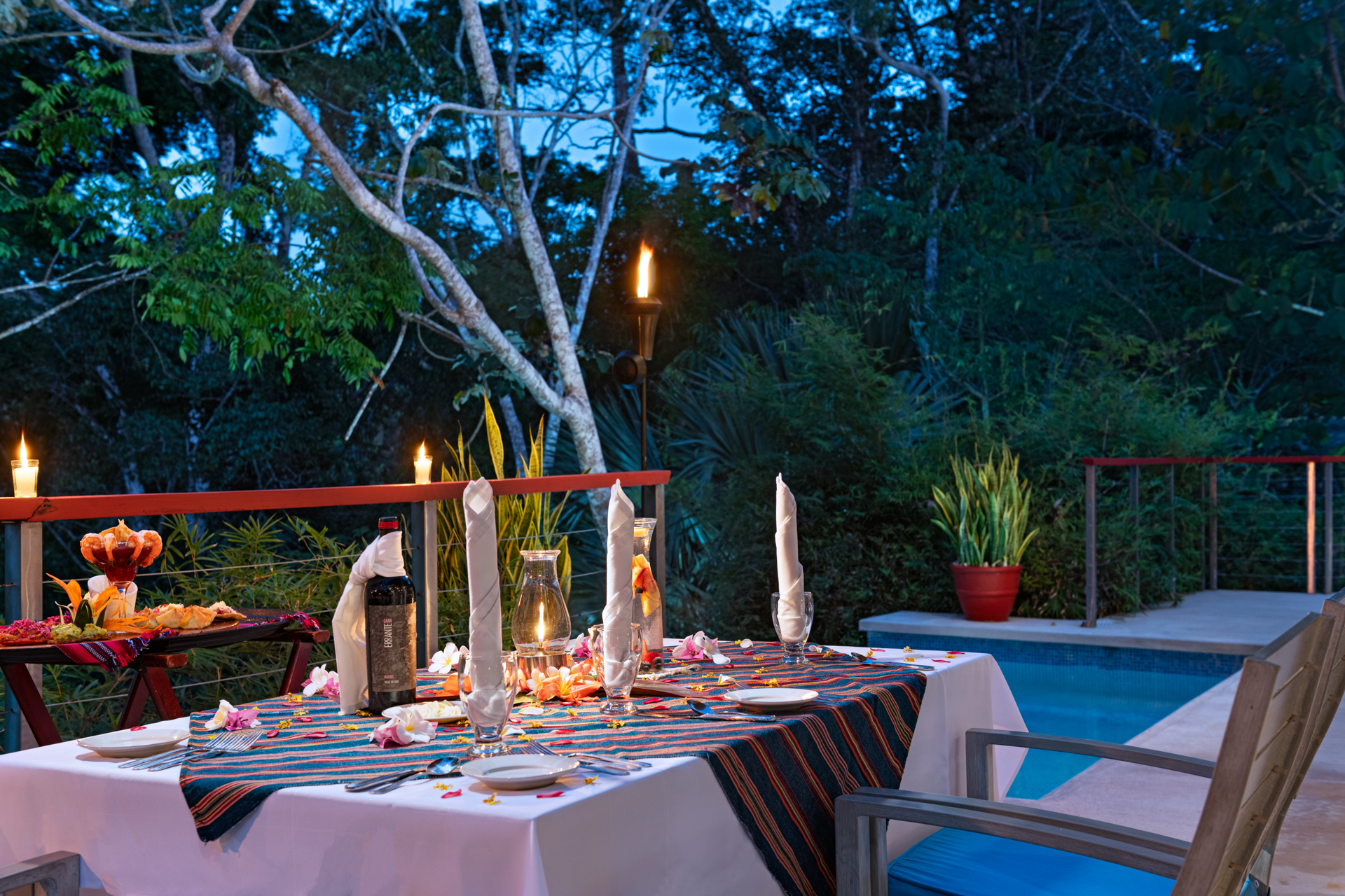 Romantic private dinner setup outside the Ix Chel Villa at The Lodge at Chaa Creek in Belize, overlooking the rainforest at sunset.