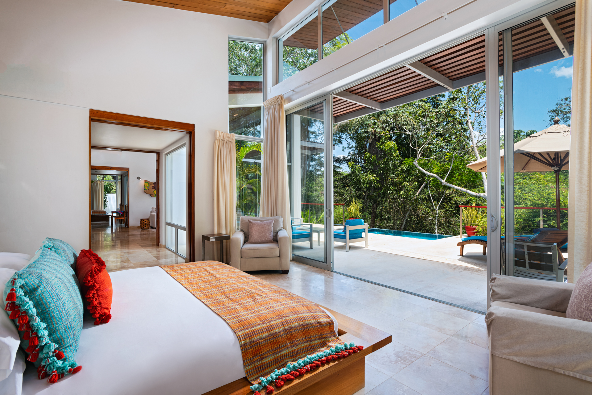 Spacious bedroom inside the Ix Chel Villa at The Lodge at Chaa Creek in Belize with panoramic jungle views through large glass doors.